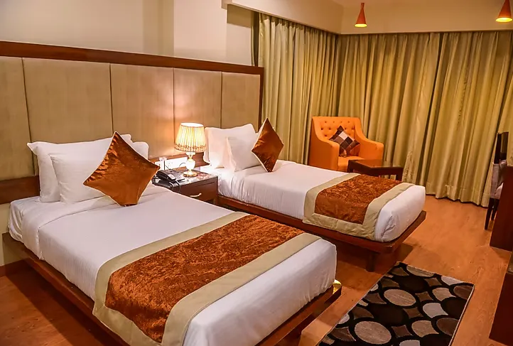 Deluxe room at Hotel Indo Prime Jaipur with twin or double bed and side tables