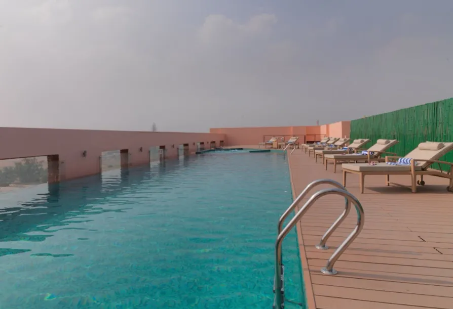Swimming pool at Hotel Royal Orchid Jaipur with poolside seating and open view