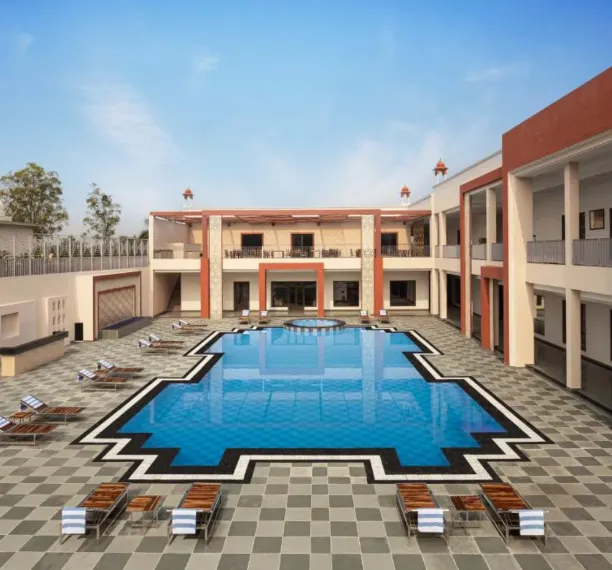 Swimming pool at Bookmark Resorts Jogi Mahal Ranthambore with deck chairs and clear water