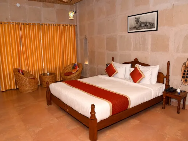 Deluxe room at Puratan Qila Ranthambore featuring bed, seating, and natural lighting