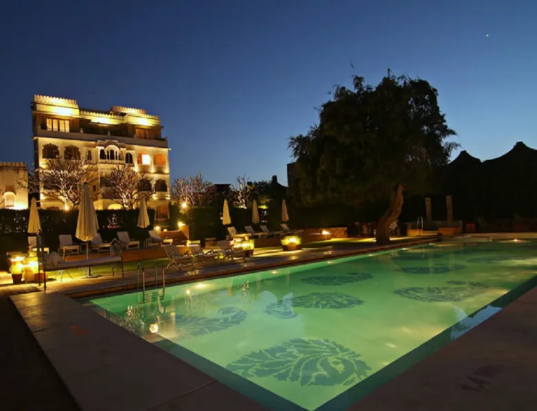Swimming pool at Rawla Narlai Luxury Heritage Hotel Kumbhalgarh surrounded by stone deck and seating