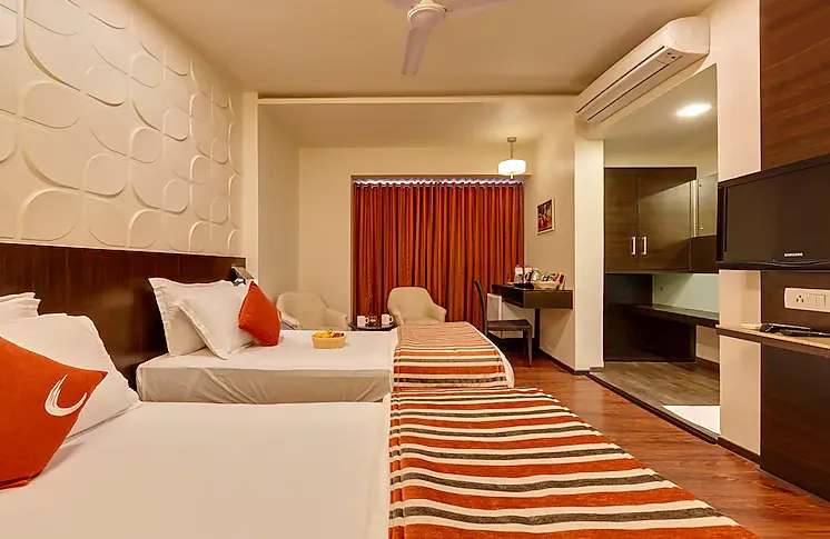Deluxe room interior at Regenta Place Raysons Kolhapur with modern bed and seating area