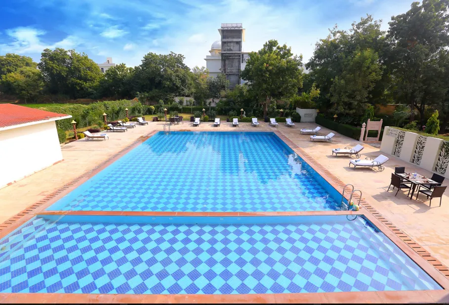Outdoor swimming pool at Regenta Resort Vanya Mahal Ranthambore with deck chairs and clear water